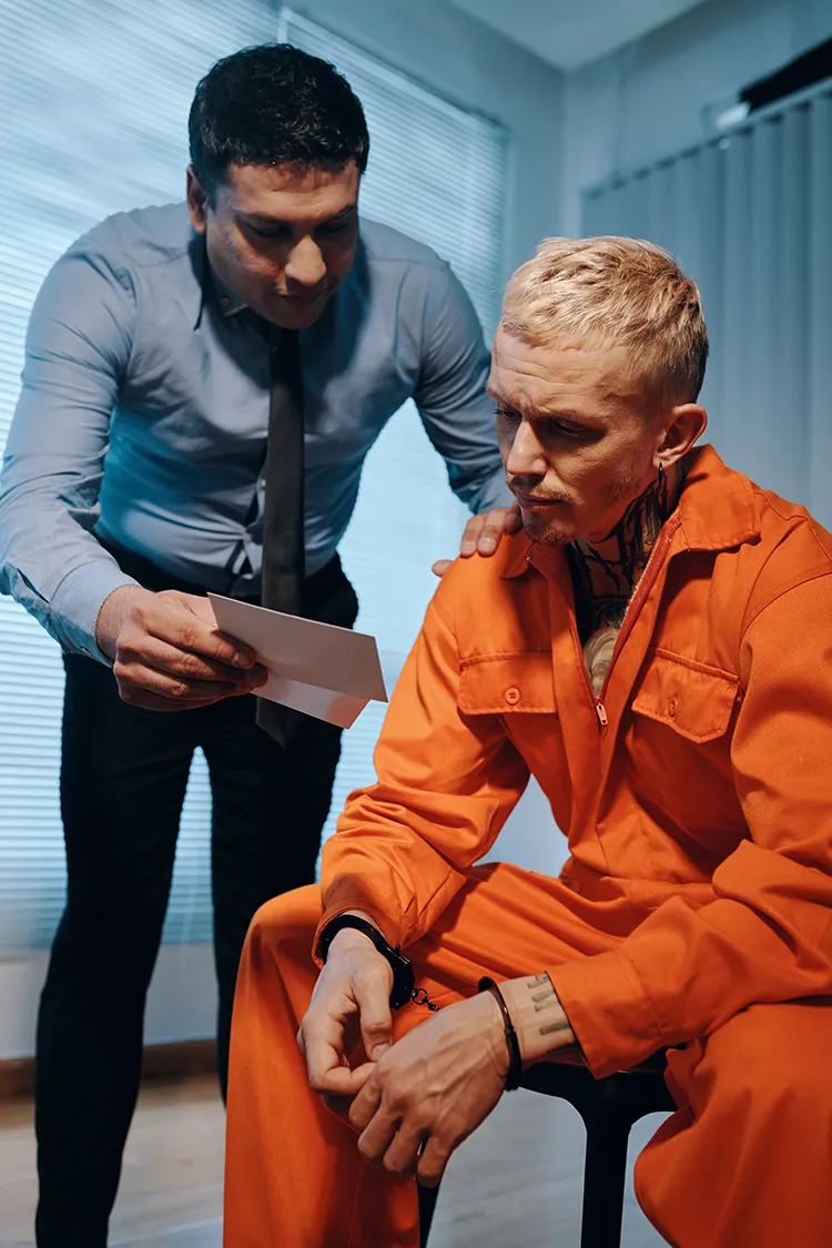 Officer talking to prisoner in orange jumpsuit.